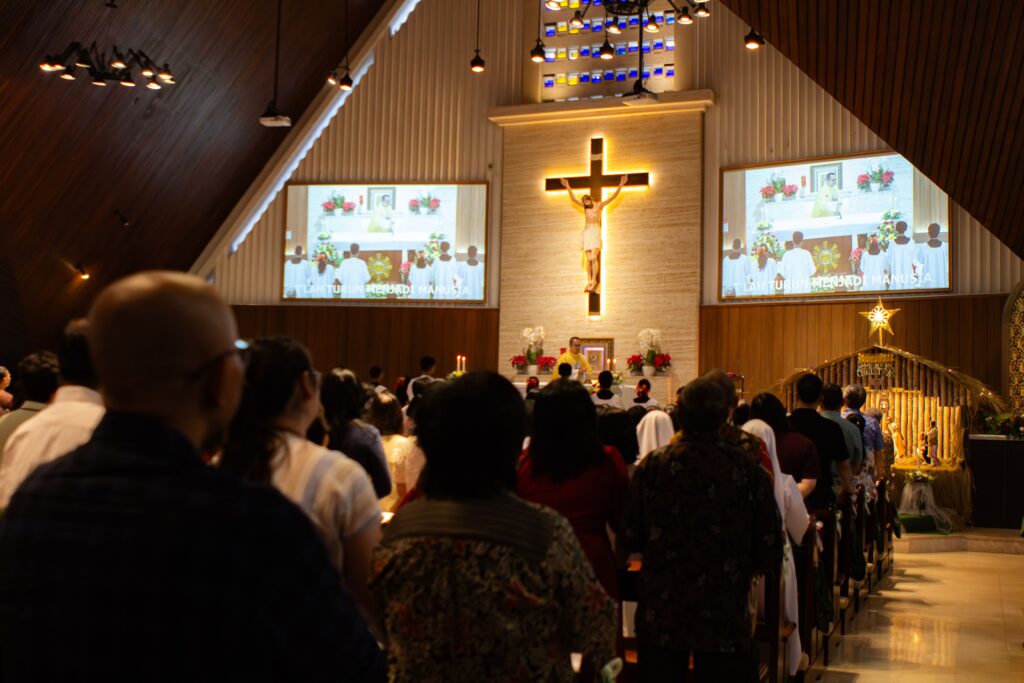 Congregation attending a Christmas Mass in a beautifully decorated Roman Catholic church.